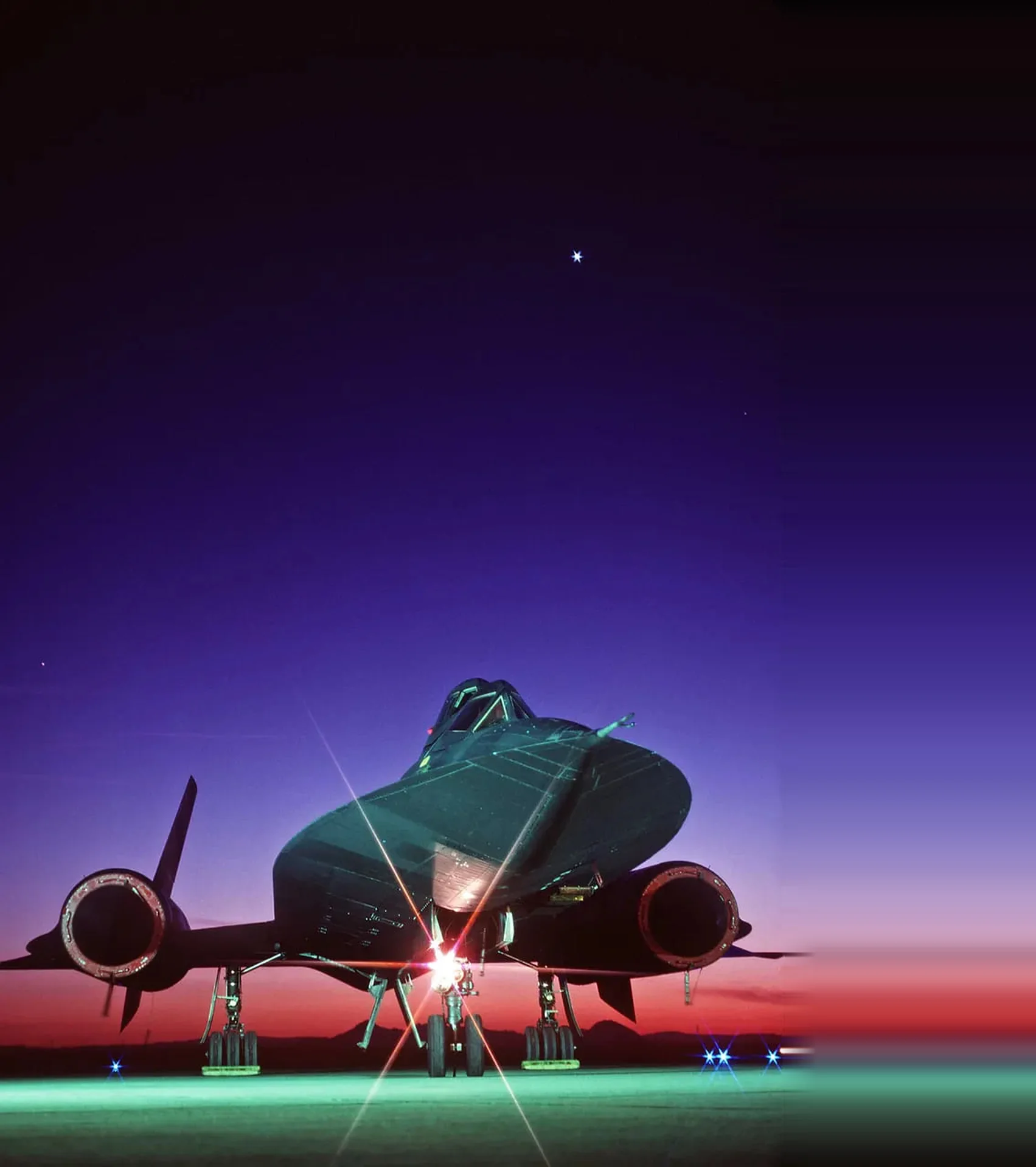 A reconnaissance jet on the ramp at dusk, seen nose-on under a violet sky
