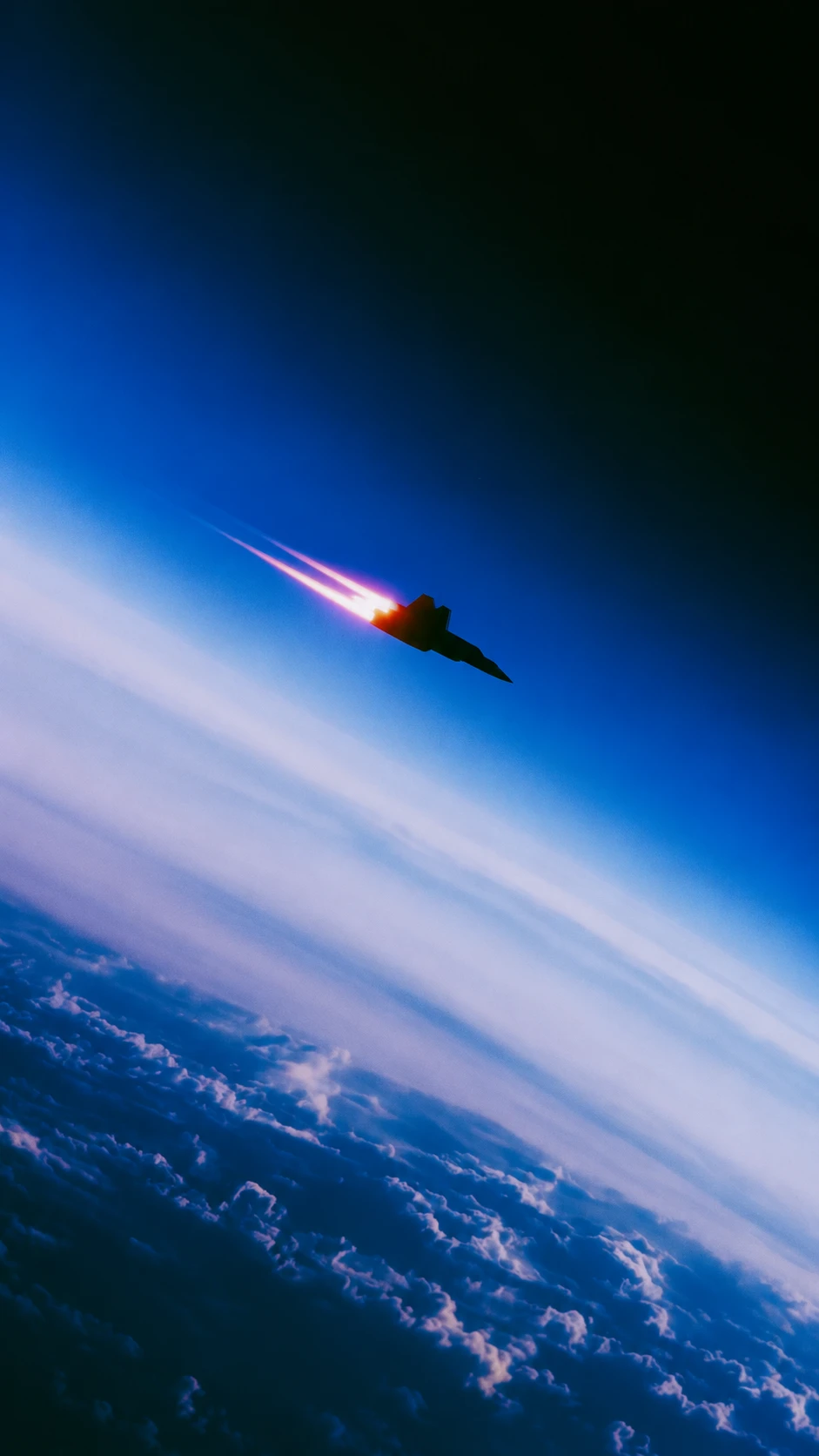 Jet silhouette with afterburner climbing along the blue atmospheric limb